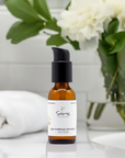 Sans Skincare Eye Makeup Remover with CoQ10 in amber pump bottle on bathroom counter with white towel and flowers