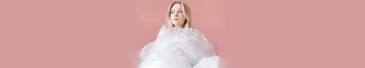 Woman wrapped in clear plastic standing against a pink background