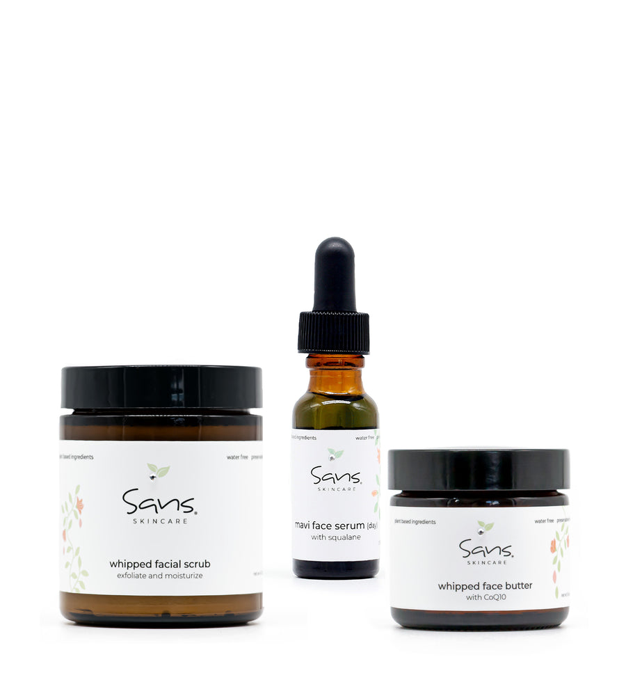 Sans Skincare Fall Renewal Ritual set — featuring three products: Whipped Facial Scrub in a brown jar with black lid, Mavi Face Serum in an amber glass bottle with a black dropper, and Whipped Face Butter in a smaller brown jar. Displayed against a clean white background, highlighting the minimalist, natural aesthetic of the brand.